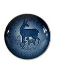 Blue ceramic plate with deer design on a textured beige surface