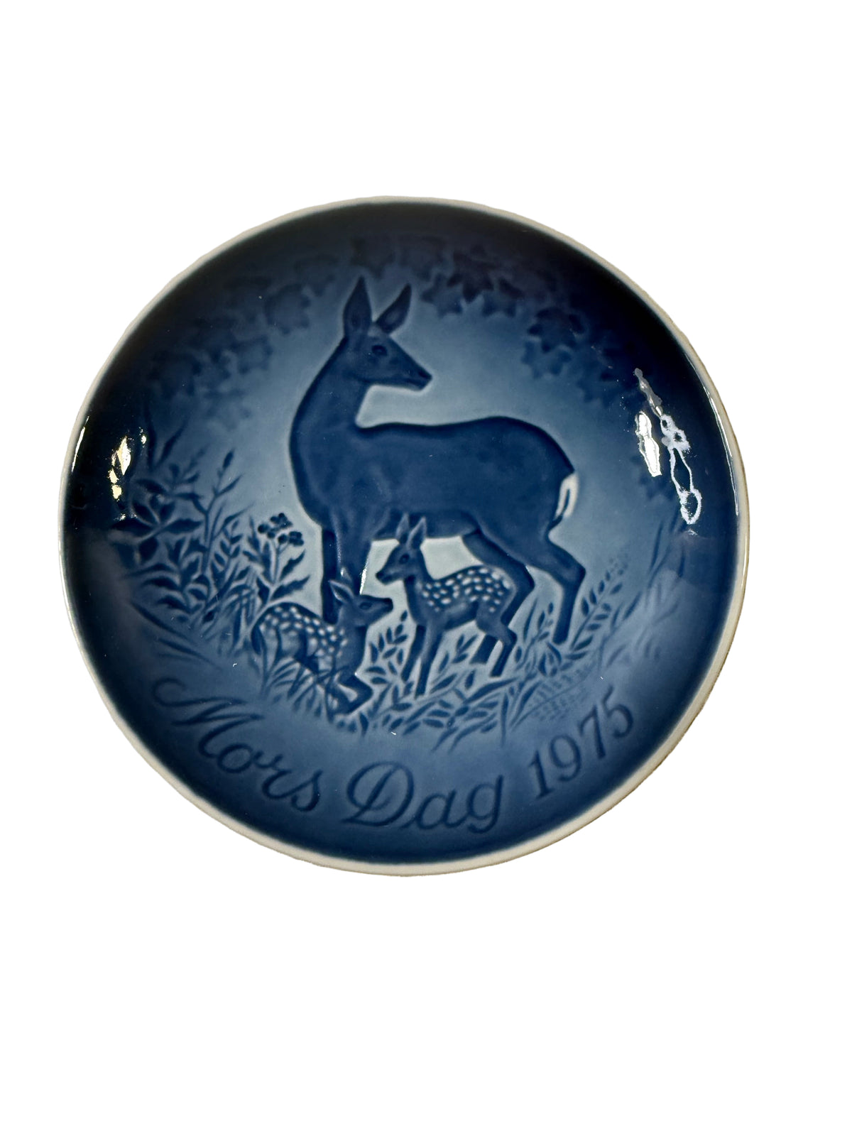 Blue ceramic plate with deer design on a textured beige surface