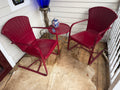 Pair of maroon shell-back steel spring chairs with round side table on porch